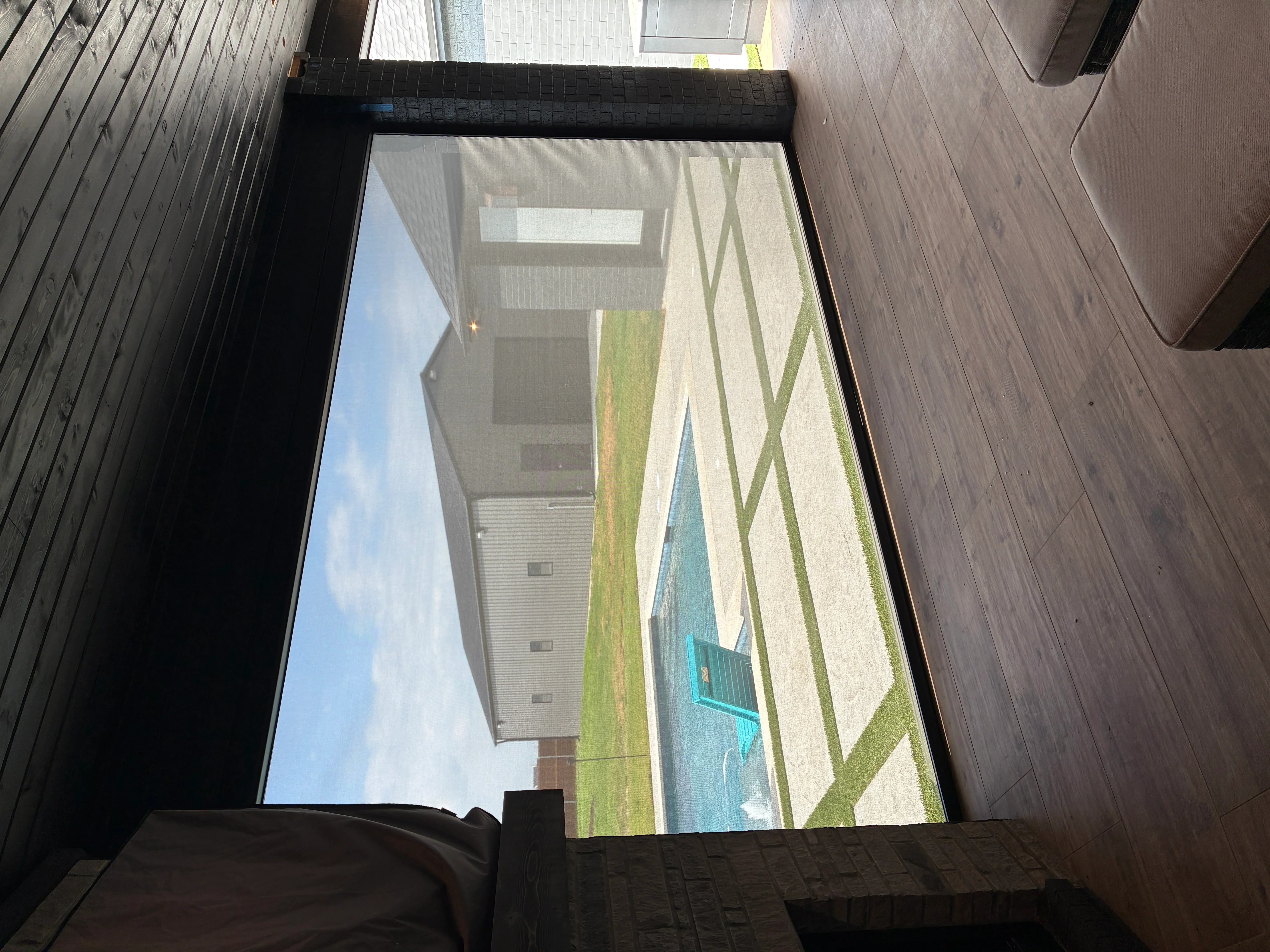 Black-framed window blind installed on large residential picture window with exterior landscape view
